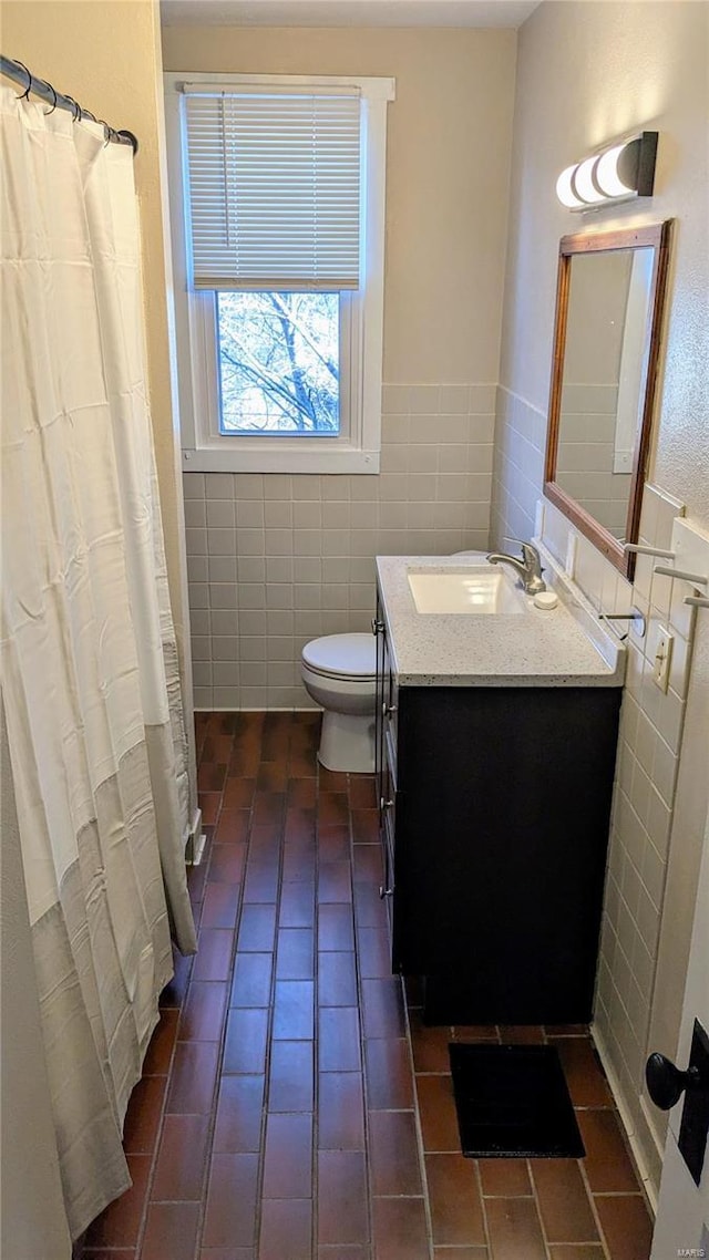 full bath featuring wainscoting, toilet, tile walls, and vanity