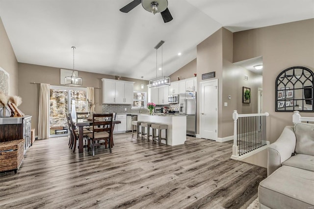 dining space with ceiling fan, high vaulted ceiling, and light hardwood / wood-style floors