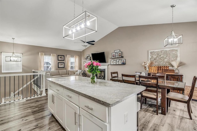 kitchen featuring white cabinetry, lofted ceiling, light hardwood / wood-style flooring, a kitchen island, and pendant lighting