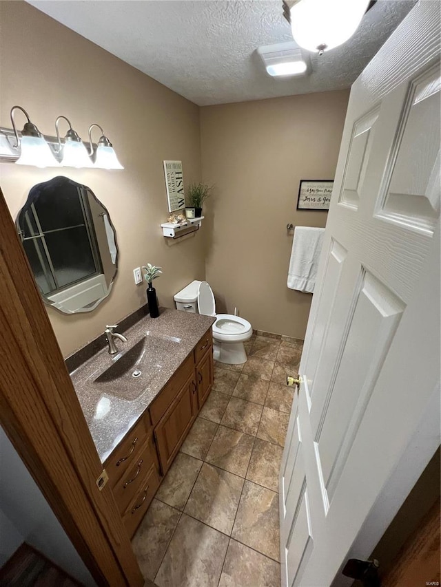 bathroom featuring toilet, tile patterned floors, vanity, and a textured ceiling