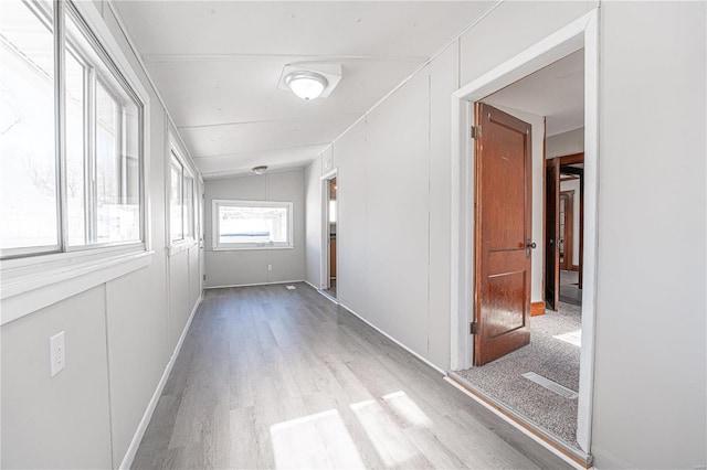 hallway featuring vaulted ceiling and light hardwood / wood-style flooring