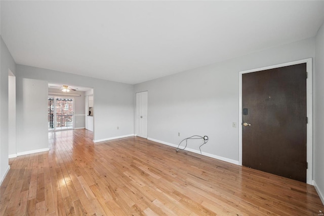 spare room with light wood-style flooring, a ceiling fan, and baseboards