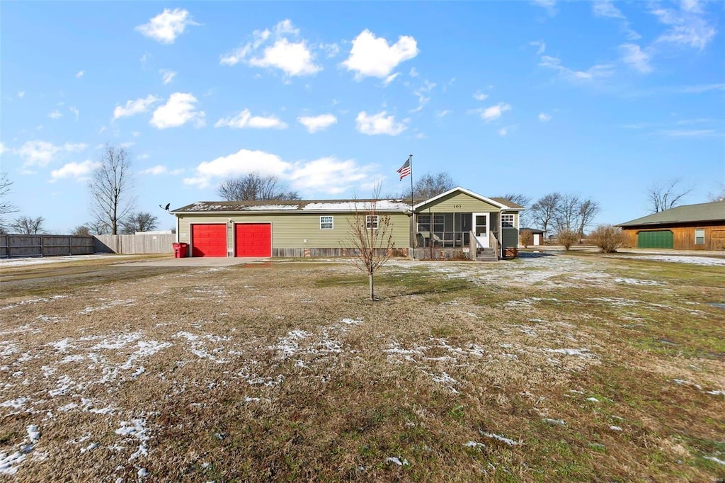 rear view of property with a garage, a sunroom, and a yard