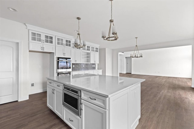 kitchen with light stone counters, hanging light fixtures, and white cabinets