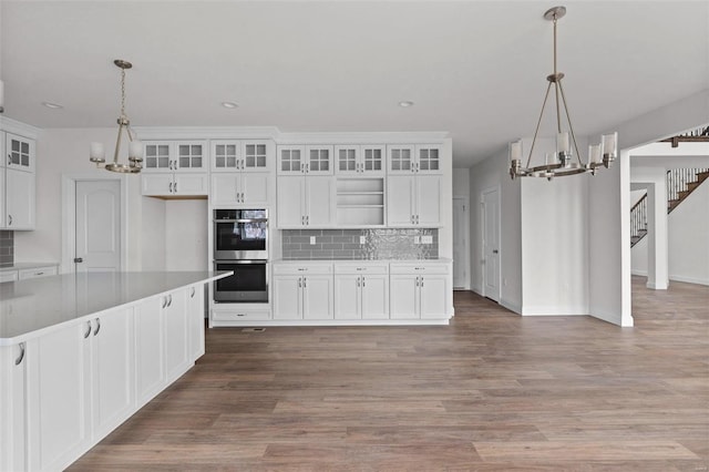 kitchen with a notable chandelier, decorative light fixtures, white cabinetry, and double oven