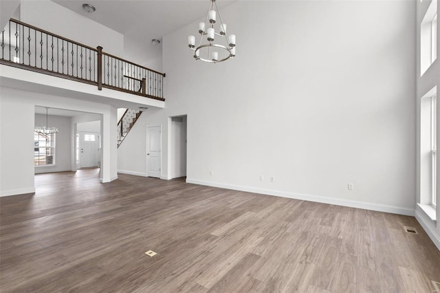 unfurnished living room with a chandelier, hardwood / wood-style flooring, and a towering ceiling