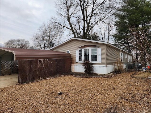 view of property exterior with concrete driveway, fence, and a detached carport