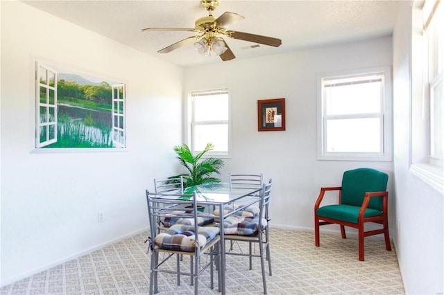 dining area with a textured ceiling, light colored carpet, visible vents, baseboards, and a ceiling fan