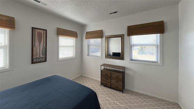 bedroom with baseboards, visible vents, and light colored carpet