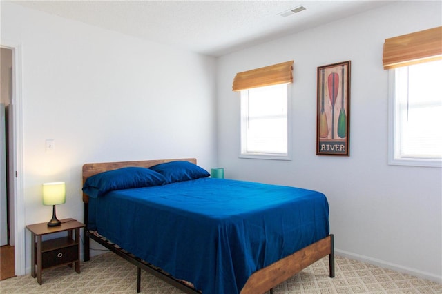 bedroom with carpet, multiple windows, visible vents, and baseboards