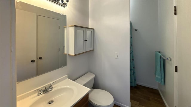 bathroom with baseboards, vanity, toilet, and wood finished floors