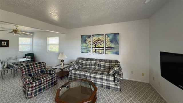 carpeted living area with a ceiling fan, baseboards, and a textured ceiling