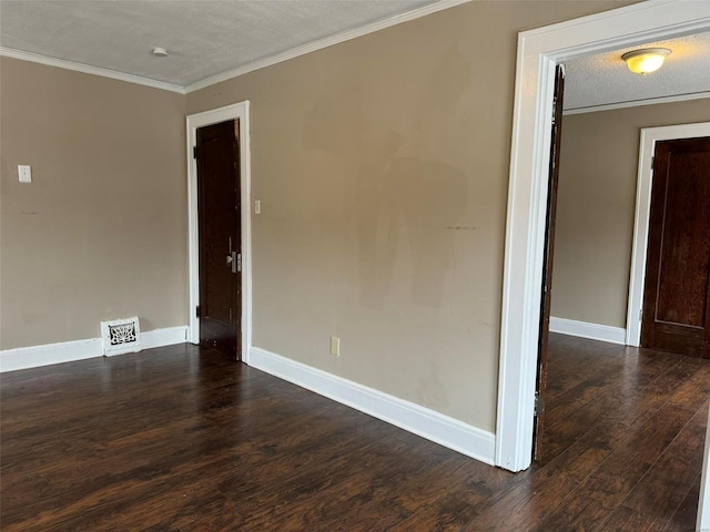 empty room with visible vents, dark wood-style flooring, crown molding, and baseboards
