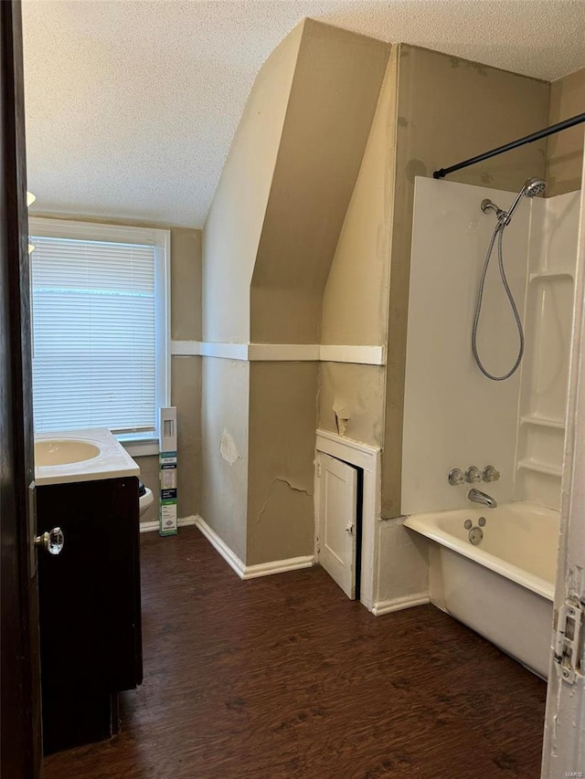 full bathroom featuring vanity, wood finished floors, baseboards, a textured ceiling, and shower / bath combination