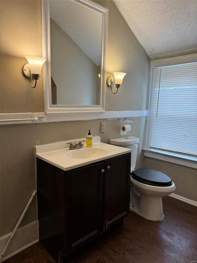 bathroom featuring a textured ceiling, vaulted ceiling, wood finished floors, vanity, and toilet