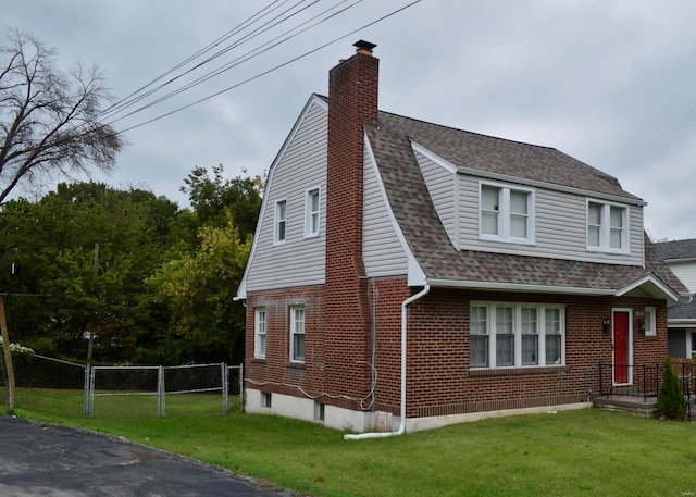 view of home's exterior featuring fence, a chimney, a yard, and brick siding