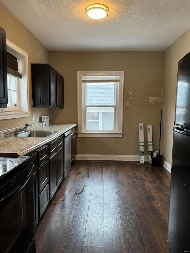 kitchen featuring a sink, dark wood finished floors, black appliances, and light countertops