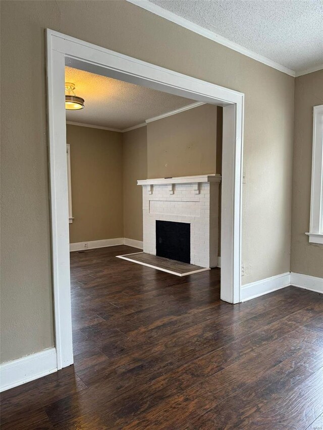 unfurnished living room featuring a textured ceiling, crown molding, a fireplace, wood finished floors, and baseboards