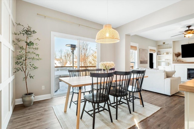 dining room with baseboards, a fireplace, dark wood finished floors, and a healthy amount of sunlight