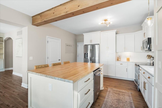 kitchen with arched walkways, appliances with stainless steel finishes, a center island, and white cabinets