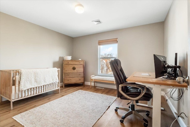 office space with wood finished floors, visible vents, and baseboards