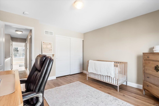 bedroom with light wood-style flooring, a closet, visible vents, and baseboards