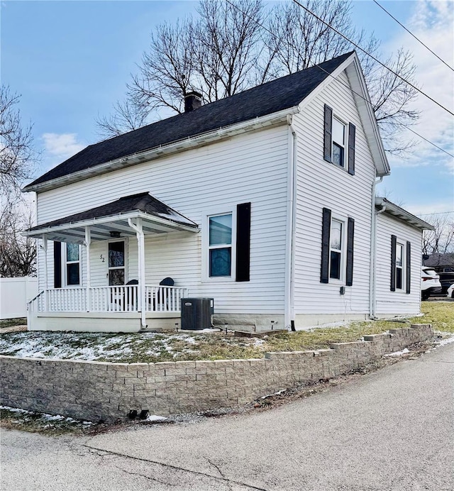 view of front facade with central air condition unit, a chimney, and a porch