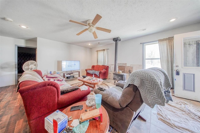 living room with a wood stove, ceiling fan, a textured ceiling, and recessed lighting