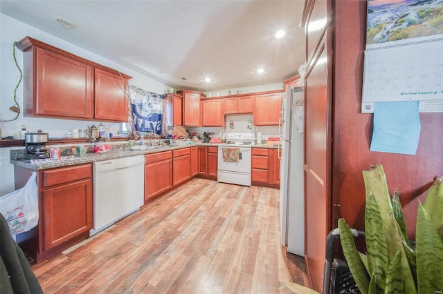 kitchen featuring recessed lighting, light wood-style floors, a sink, light stone countertops, and white appliances