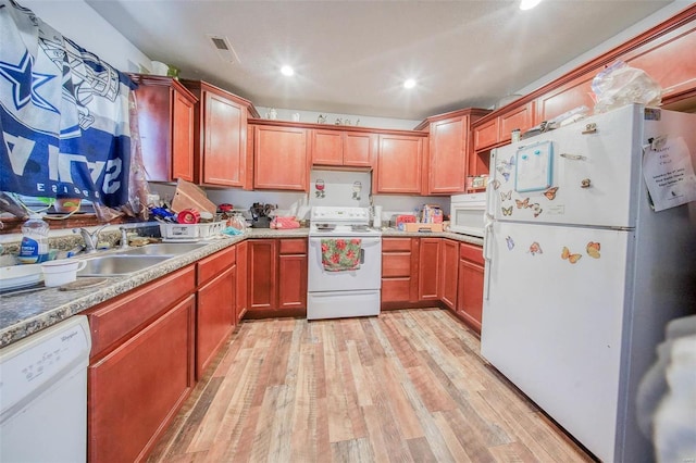 kitchen with white appliances, light countertops, a sink, and light wood finished floors