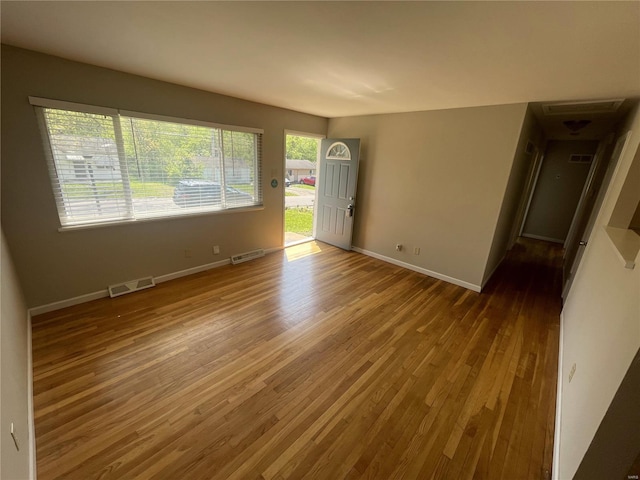 unfurnished room featuring wood finished floors, visible vents, and baseboards