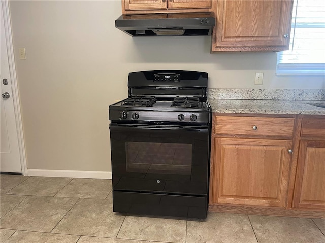 kitchen featuring extractor fan, black range with gas stovetop, brown cabinetry, and light stone countertops