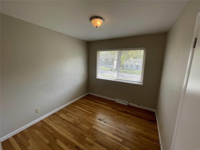 empty room with visible vents, baseboards, and wood finished floors