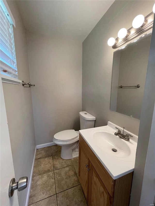 bathroom featuring tile patterned flooring, baseboards, vanity, and toilet