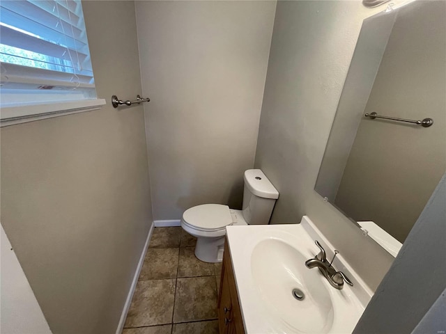 half bathroom with toilet, tile patterned flooring, baseboards, and vanity