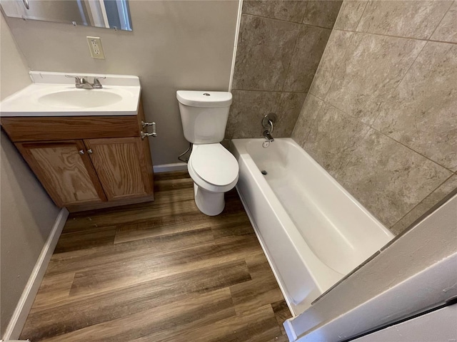 bathroom with baseboards, toilet, wood finished floors, tub / shower combination, and vanity