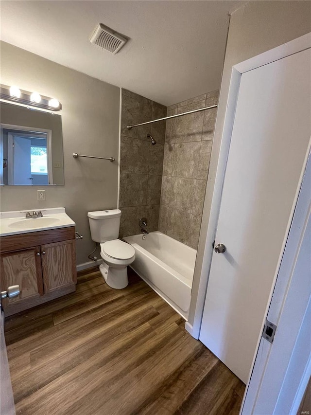 full bath featuring toilet, wood finished floors, vanity, visible vents, and  shower combination