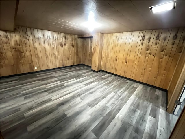finished below grade area featuring wood walls, baseboards, and wood finished floors