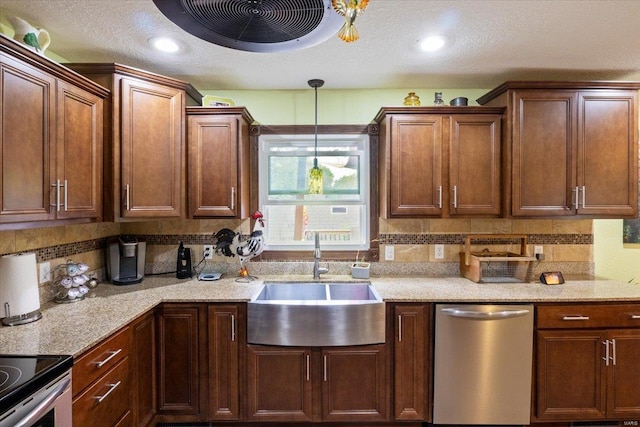 kitchen with appliances with stainless steel finishes, sink, hanging light fixtures, light stone countertops, and tasteful backsplash