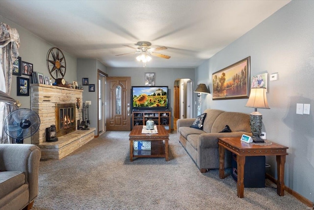 carpeted living room with a fireplace and ceiling fan