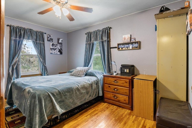 bedroom with light wood-type flooring, ceiling fan, and multiple windows