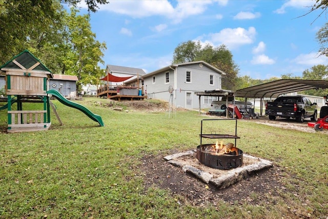 view of yard with an outdoor fire pit, a playground, and a carport