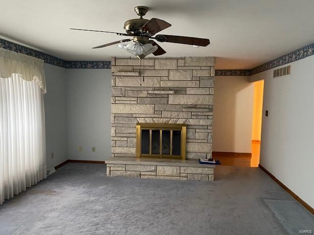 unfurnished living room featuring ceiling fan, carpet floors, and a fireplace