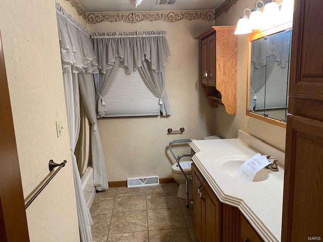 full bathroom with shower / tub combo with curtain, toilet, vanity, and tile patterned flooring