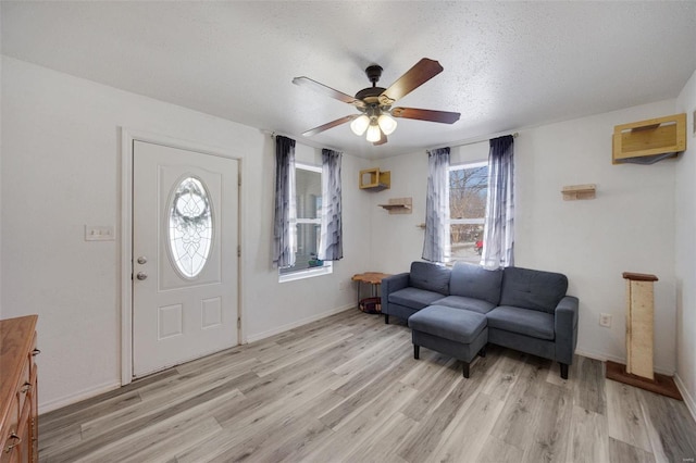 foyer featuring light wood-style floors, a wall unit AC, plenty of natural light, and ceiling fan