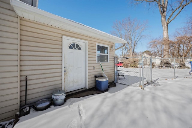 snow covered property entrance with fence and a patio