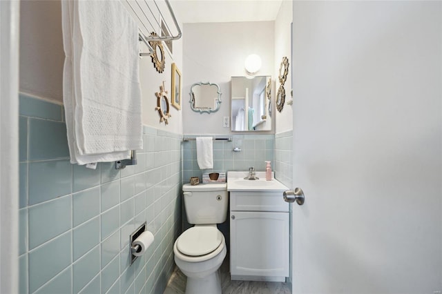 bathroom with toilet, tile walls, and vanity