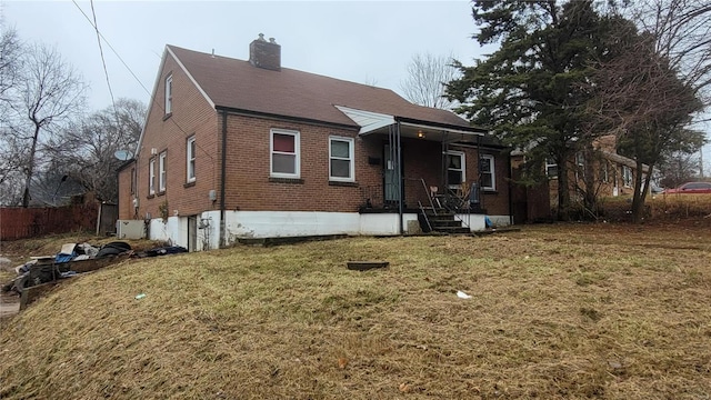 bungalow-style house with brick siding, a chimney, and a front yard