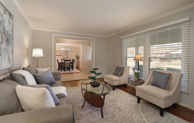 living room featuring visible vents, ornamental molding, wood finished floors, an inviting chandelier, and baseboards