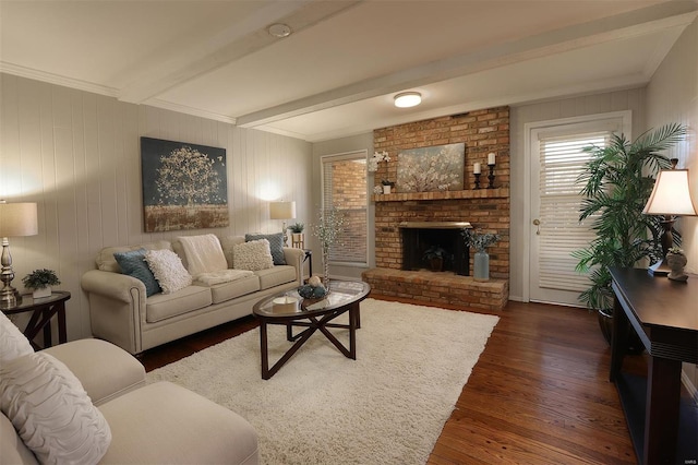 living room with beam ceiling, dark wood-type flooring, a brick fireplace, and crown molding